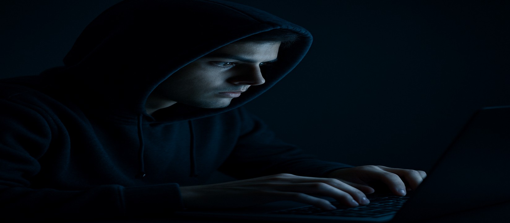 mcw login ওয়েবসাইটে অনলাইন গেম খেলার জন্য একজন ব্যক্তি অন্ধকার ঘরে ল্যাপটপে একাগ্র দৃষ্টিতে বসে আছেন।